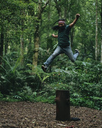 Full length of young man jumping in forest