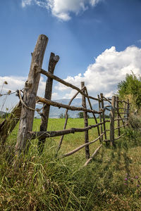 Wooden fence on field against sky