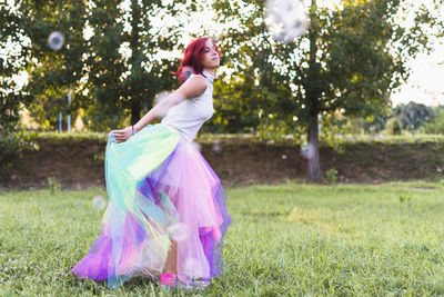 Woman dancing on field against trees