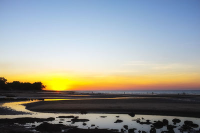 Scenic view of beach against clear sky during sunset