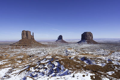 View of snow covered monument valley against clear blue sky