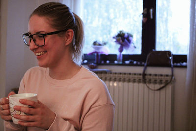 Smiling young woman having coffee at home