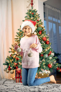 Merry christmas and new year holidays. a charming little girl decorates a christmas tree 