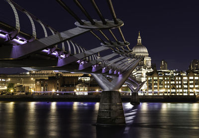 Illuminated bridge over river against sky at night