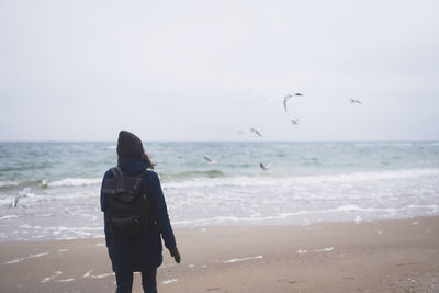 Beautiful woman walking on the beach with seagulls in winter time. free spirit concept person