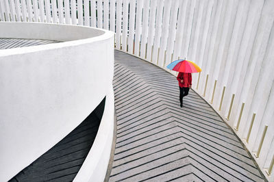A man walking with an umbrella down the carpark ramp