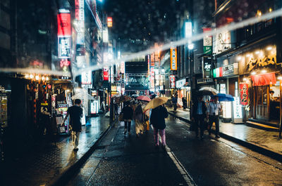 People walking on wet road in city during rainy season