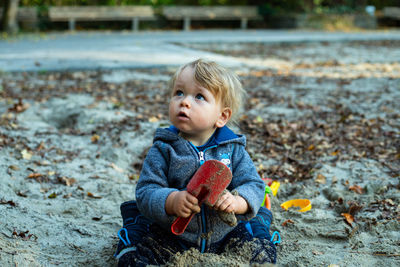 Portrait of cute boy sitting on land