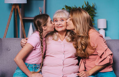 Portrait of mother and daughter kissing grandmother at home