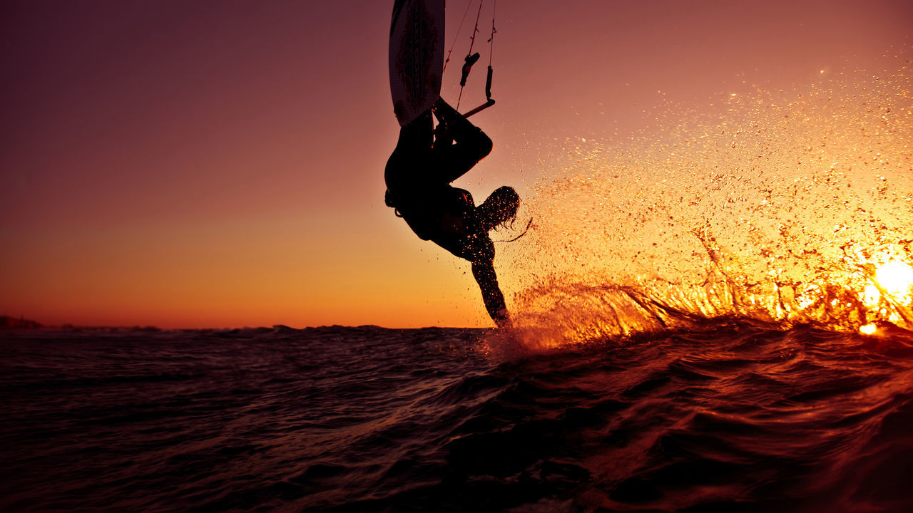 sunset, leisure activity, lifestyles, silhouette, sea, orange color, beach, sun, water, sky, person, men, motion, holding, sunlight, nature, standing, outdoors