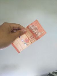 Close-up of hand holding paper over white background