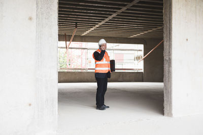 Man on the phone wearing safety vest in building under construction