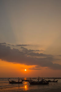 Silhouette boats moored in sea against sky during sunset