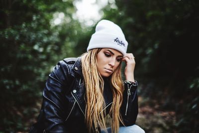 Thoughtful mid adult woman wearing hat in forest