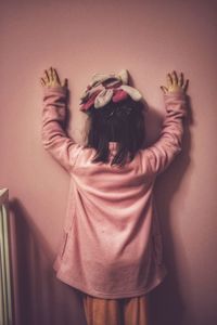 Rear view of girl standing against window at home