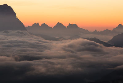 Scenic view of dramatic sky over silhouette mountains during sunset