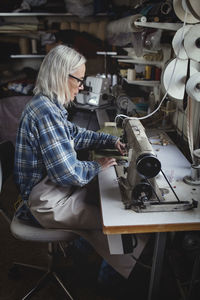 Senior owner using sewing machine at workshop