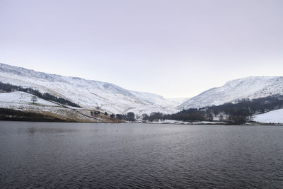 Scenic view of lake by snowcapped mountains against sky