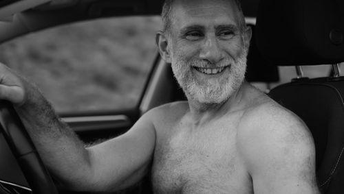 Monochrome of portrait of shirtless adult man smiling in car