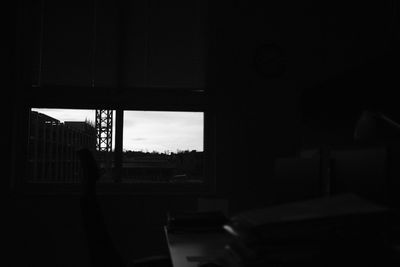 Silhouette building against sky seen through window