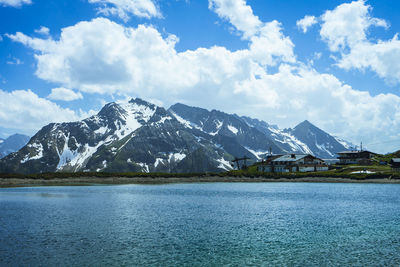 Scenic view of lake by snowcapped mountains against sky