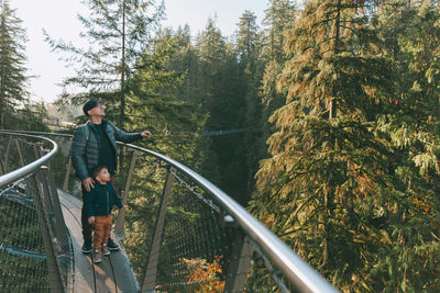 Father and son on footbridge in forest