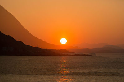 Scenic view of sea against dramatic sky during sunset