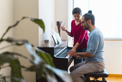 Man and woman using piano at home