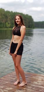 Portrait of a beautiful young woman standing at lake
