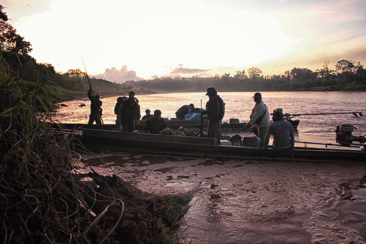 PEOPLE SITTING ON BOAT AT BEACH DURING SUNSET