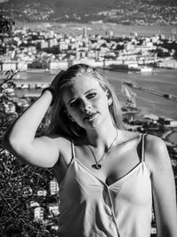 Portrait of young woman standing against cityscape