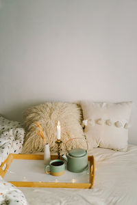 Cup of tea and teapot on a serving tray on a bed.