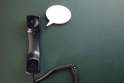 Close-up of telephone receiver with speech bubble on table