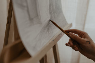 Cropped hand of man writing in book