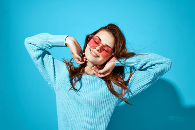 Portrait of young woman against blue background