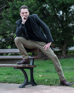 Full length portrait of man sitting on bench at park