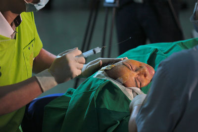 Cropped hands of doctor injecting syringe to patient in operating room