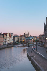 Buildings by river against clear sky