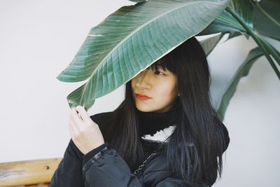 Close-up of young woman standing by plant