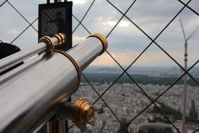 Coin-operated binocular by fence in city