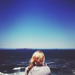 Rear view of girl at sea against clear sky