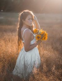 Young woman holding flower on field