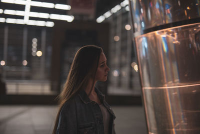 Woman by metal with reflection at night