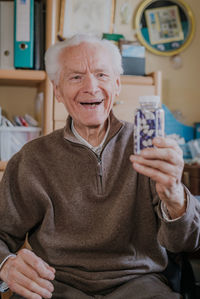 Portrait of smiling man holding camera at home