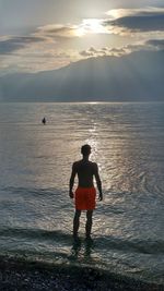 Silhouette man standing on beach against sky during sunset