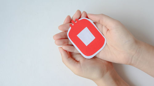 Cropped hand of person holding smart phone against white background