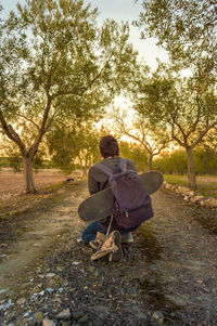 Rear view of man sitting on road against trees