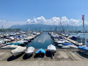 Boats moored at harbor against blue sky