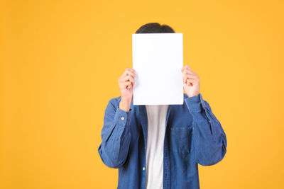 Mid section of person holding paper against wall