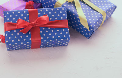 Boxes packed in festive blue paper and tied with silk ribbon on white background, birthday gift